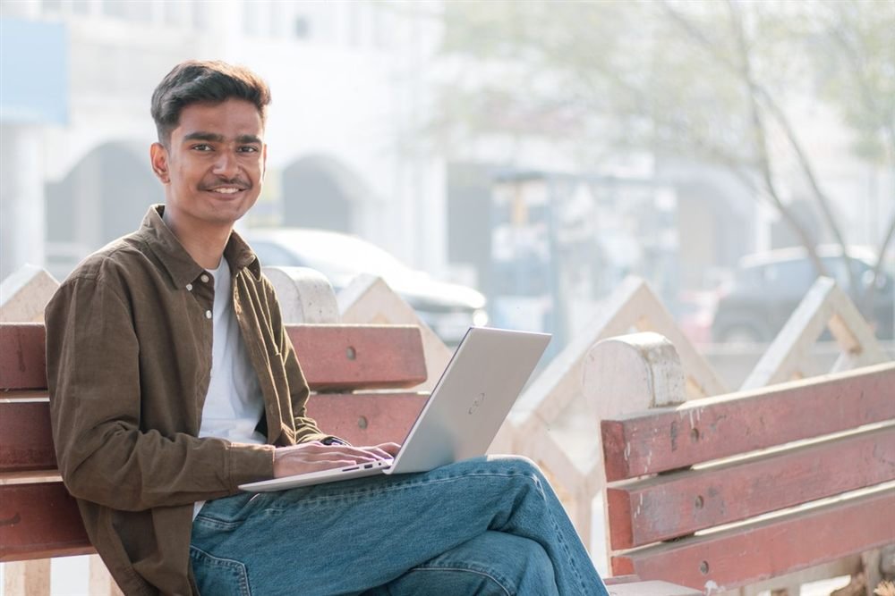 Young Indian graduate smiling with laptop after completing an online degree