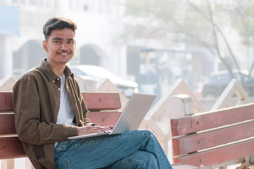 Young Indian graduate smiling with laptop after completing an online degree